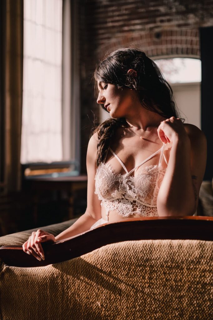 Woman in white boudoir lingerie on a couch by a window