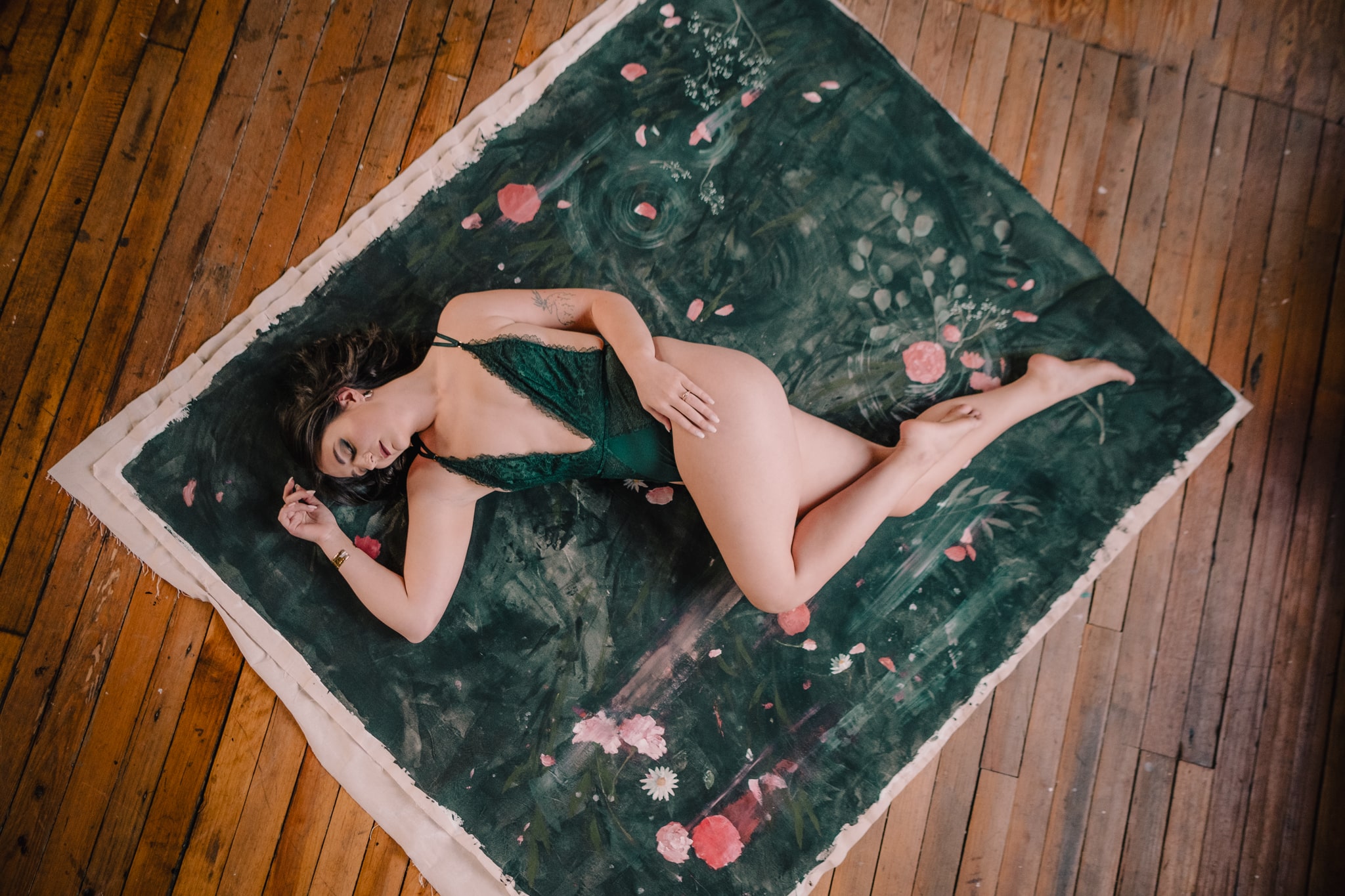 Woman lies on a green painted canvas during a boudoir photography session